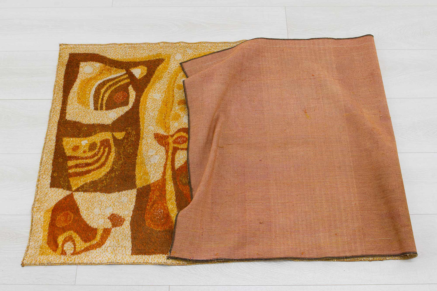 1960s vintage mid century modern wall tapestry halfway folded over, showcasing the organic abstract design in orange, brown and beige colors and the woven underside of the vintage fabric