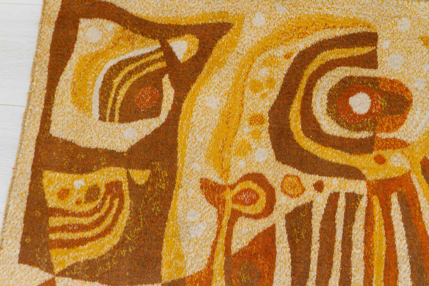 Closeup shot of a vintage mid century modern wall tapestry, showcasing the organic abstract design in orange, brown and beige colors and the fine pile structure of the vintage tapestry fabric