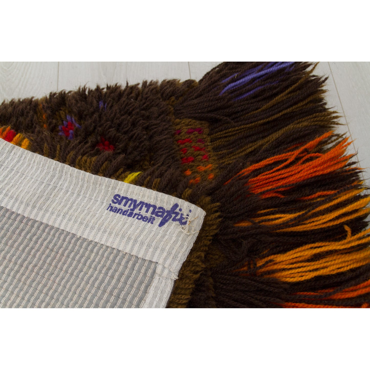 An extreme macro close up of the corner on the backside of the tapestry, verifying the original blue "Smyrnafix Handarbeit" tag.