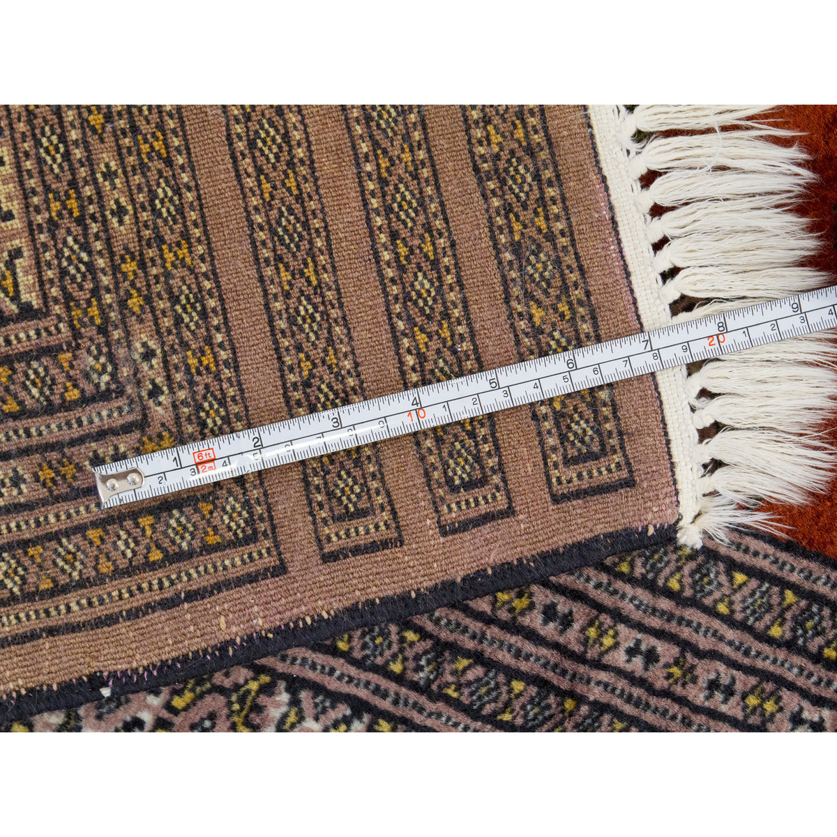 Back of hand-knotted rug with measuring tape showing the fine knot density and fringe