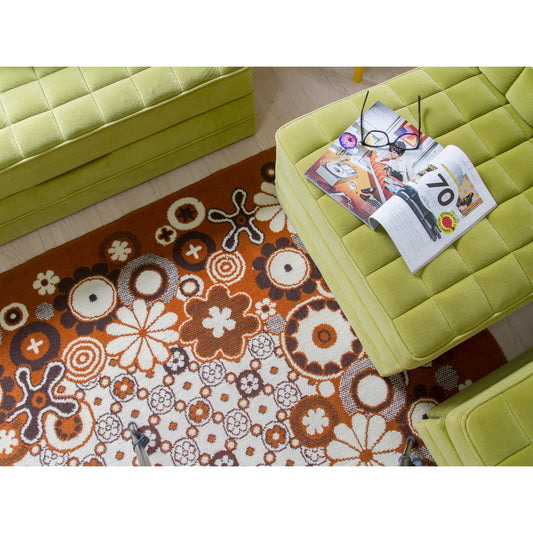 Retro 70s rug styled with a vintage magazine on a green pouf, cozy living room scene