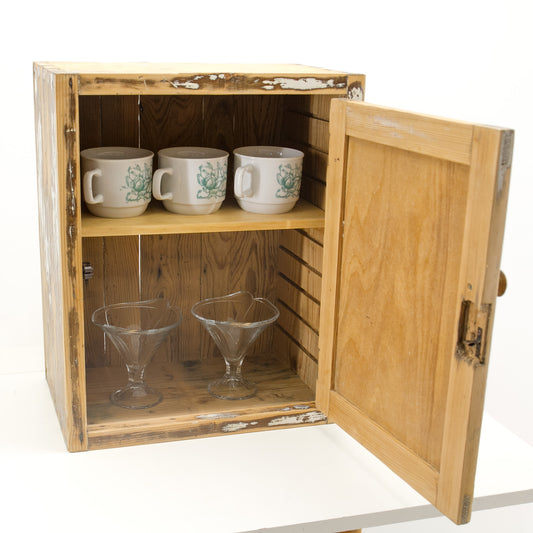 Small vintage wall cabinet for kitchen: a rustic wooden storage cabinet with a distressed finish, in traditional shaker style. The solid wood furniture is shown open with mugs on the top shelf and glasses on the bottom shelf for scale.