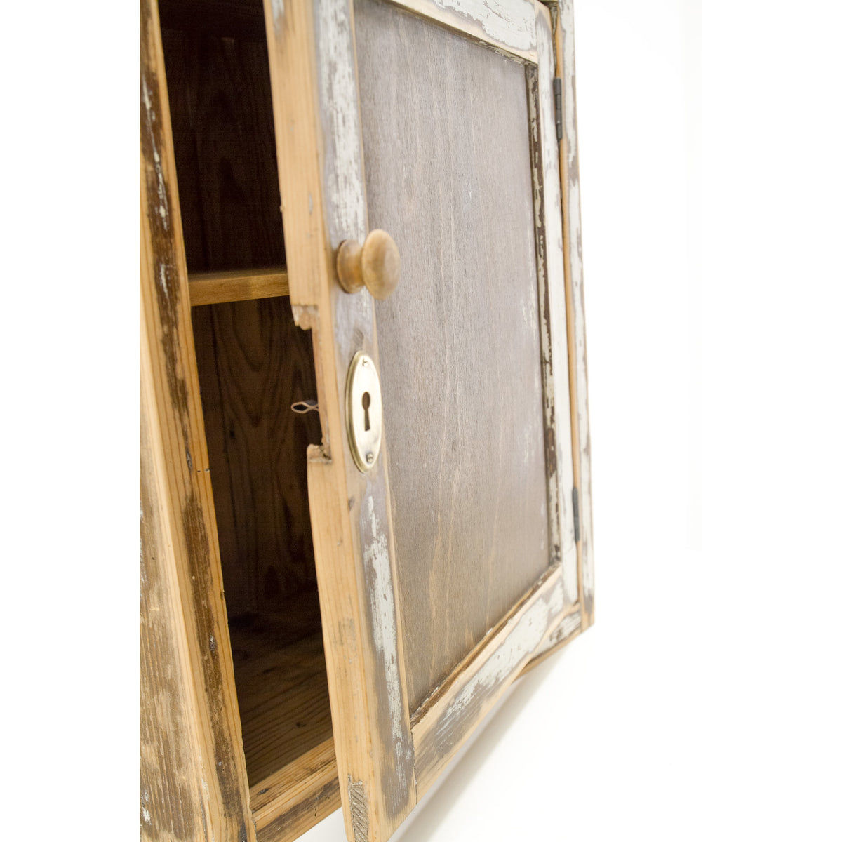 A refurbished rustic wooden wall cabinet with a distressed white and natural wood frame, shown open to reveal a wooden interior and shelf. The cabinet features a round wooden knob and a brass keyhole on the door and has an overall nostalgic rustic vibe.