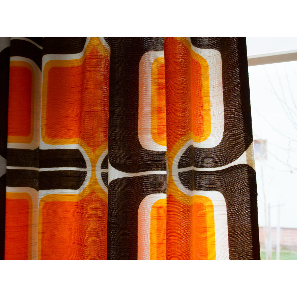 Close-up of 1970s style pop art curtain fabric with rounded rectangle motif in orange, brown and cream