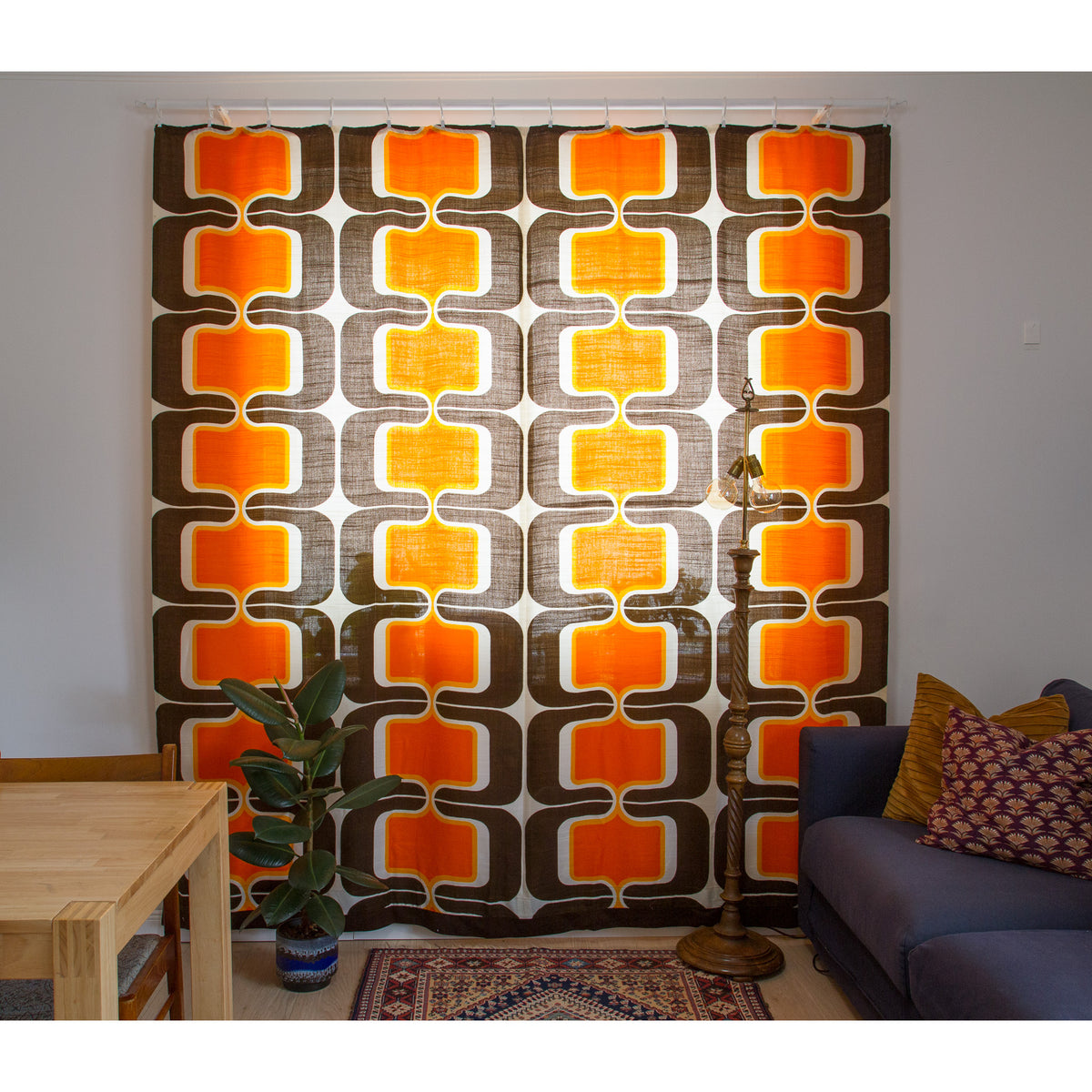 Two vintage 60s drapes closed across a full window, space age geometric pattern in orange, yellow and brown.