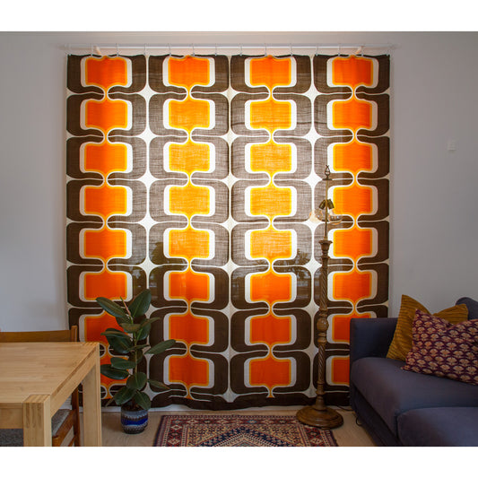 Two vintage 60s drapes closed across a full window, space age geometric pattern in orange, yellow and brown.