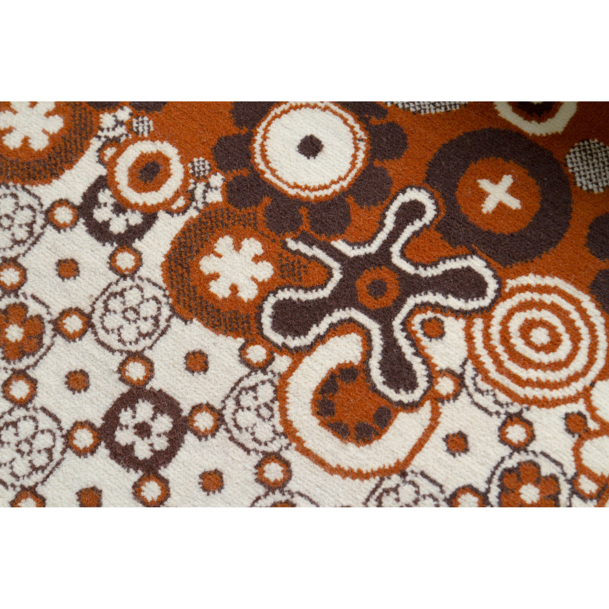 Close-up of 70s space age floral motif on rug in chocolate brown, caramel and ivory