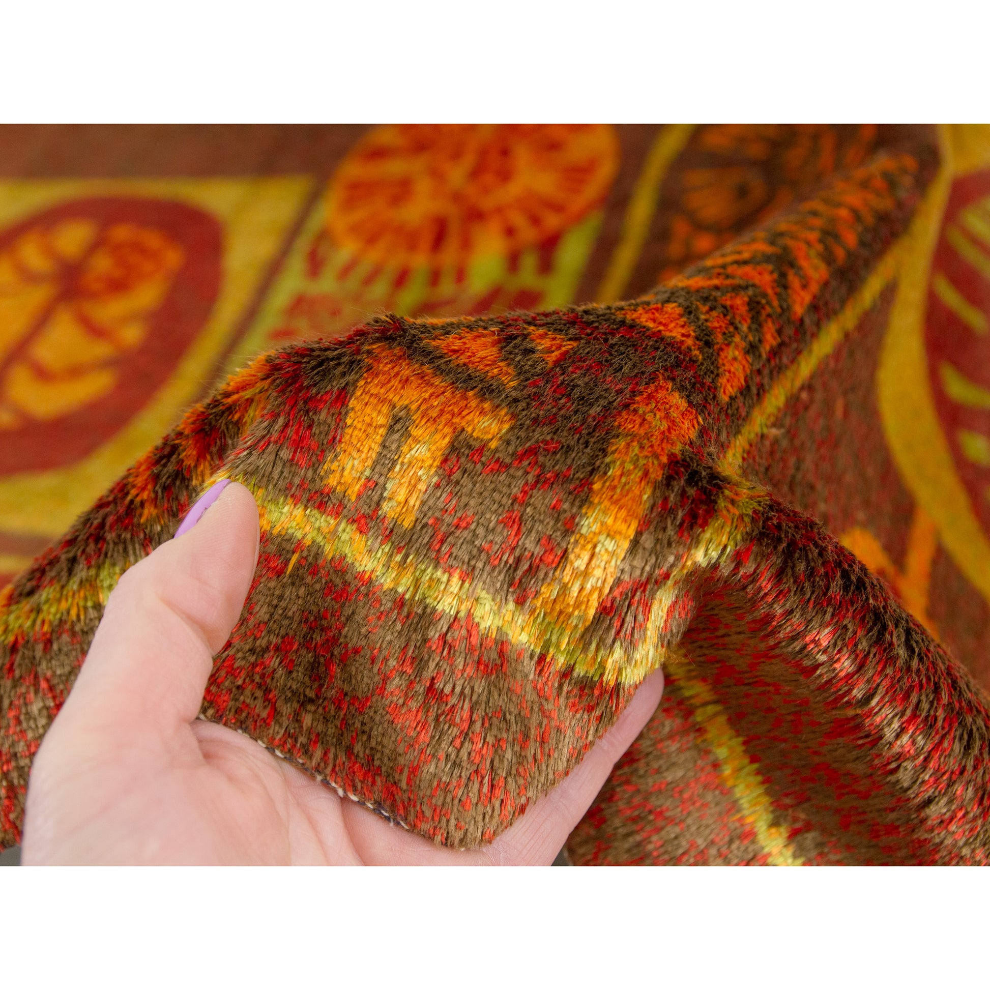 Edge of the mid century style rug held under natural light to exhibit the gentle, highly sophisticated velvet sheen characteristic of premium 60s textiles.