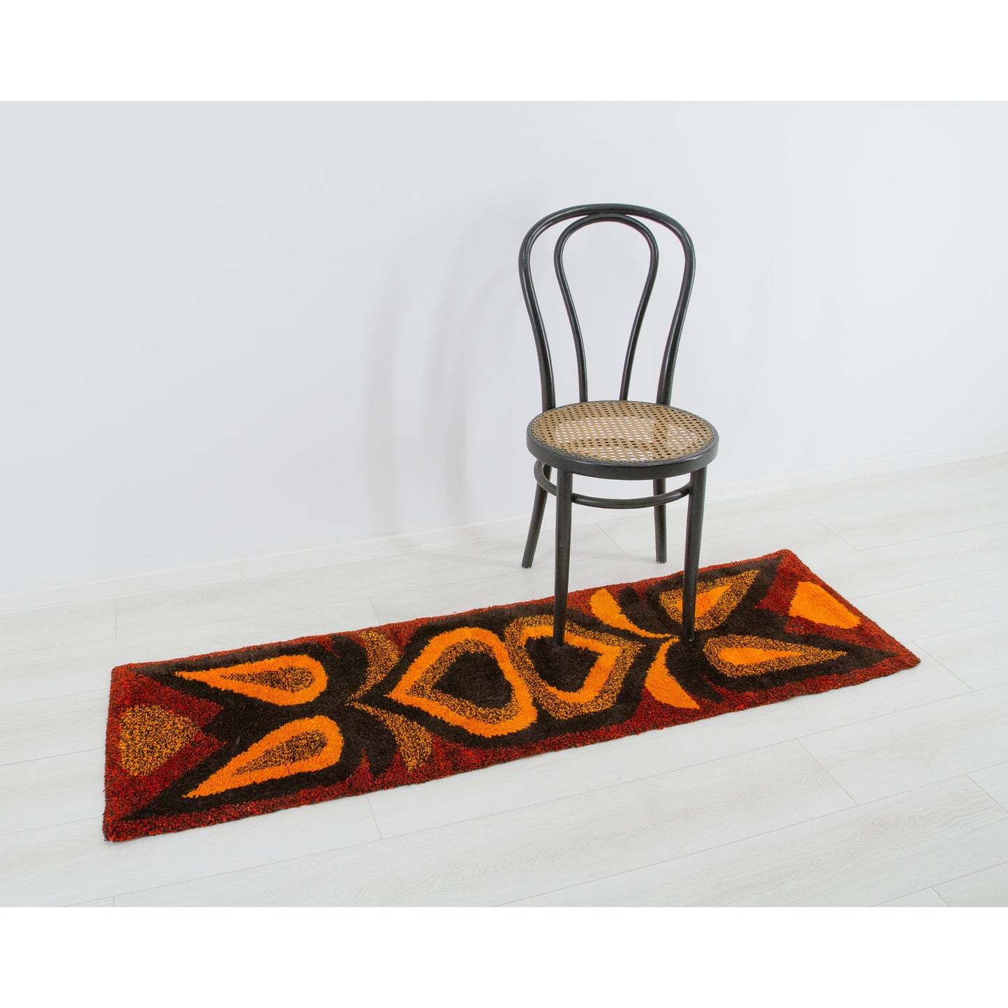 Placed magnificently as a highly tactile, vivid floor runner positioned gracefully alongside a classic caned Thonet bentwood chair in a minimal retro room.