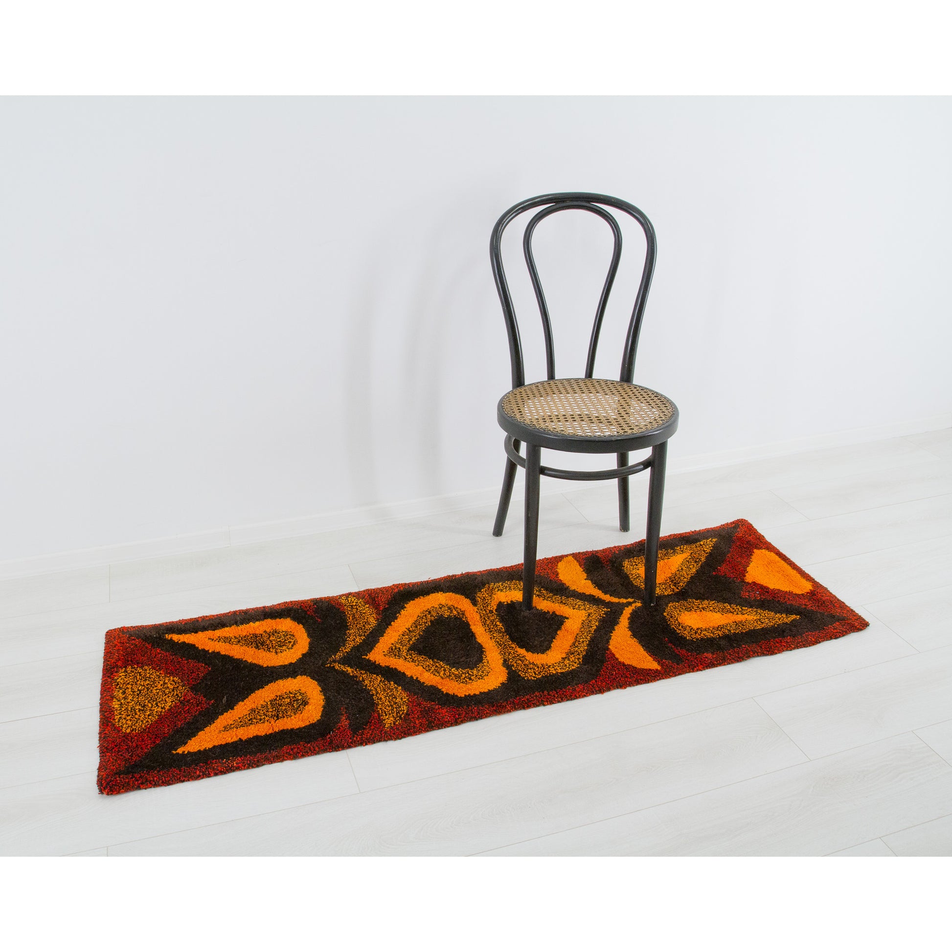 Placed magnificently as a highly tactile, vivid floor runner positioned gracefully alongside a classic caned Thonet bentwood chair in a minimal retro room.
