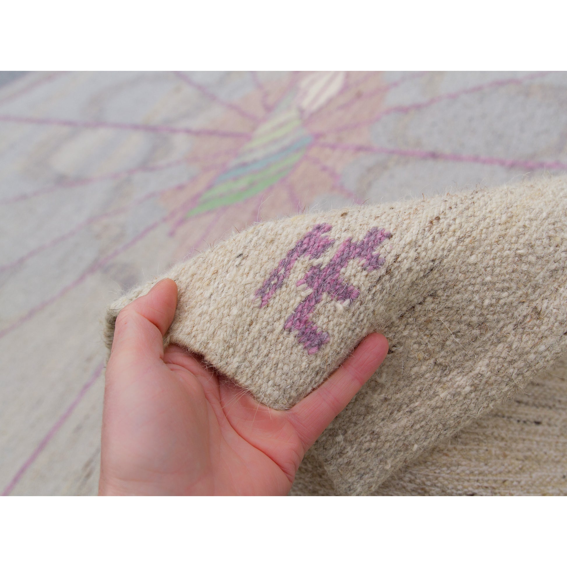Hand touching the corner to proudly display the woven "NÉ" monogram, confirming the piece as an authentic, collectible design by celebrated Hungarian textile artist Éva Németh.