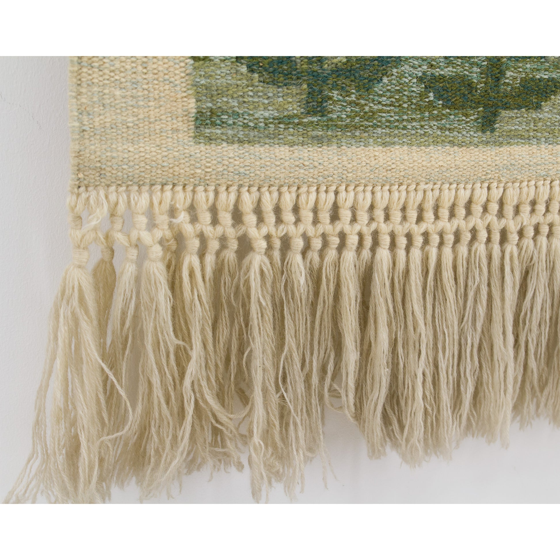 A clean, horizontal macro shot demonstrating the impressively uniform, tightly knotted row of macrame detailing finishing the woven artwork.