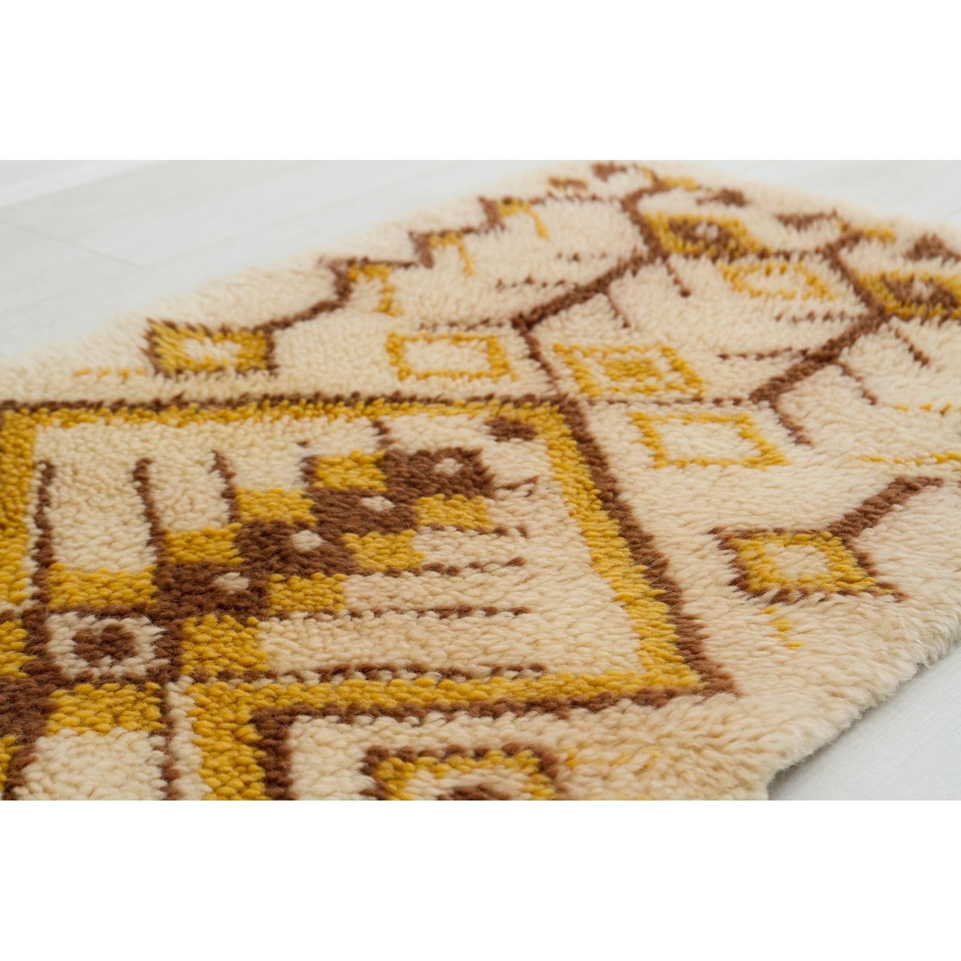 Low-angle close-up emphasizing the wonderfully fluffy dimensional peaks and valleys carved naturally between the beige base layer and the handknotted brown pattern details.