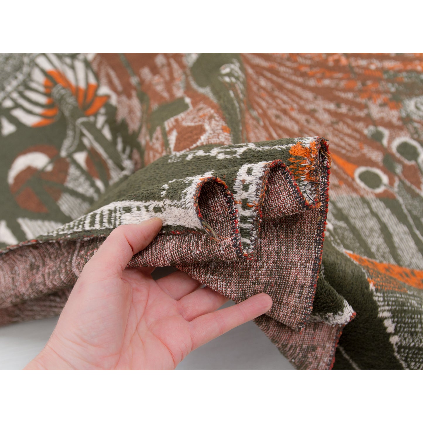 Edge of the large tapestry beautifully draped over a hand, demonstrating the perfect balance of a fabric that is delightfully soft and thin, yet undeniably sturdy and robust.