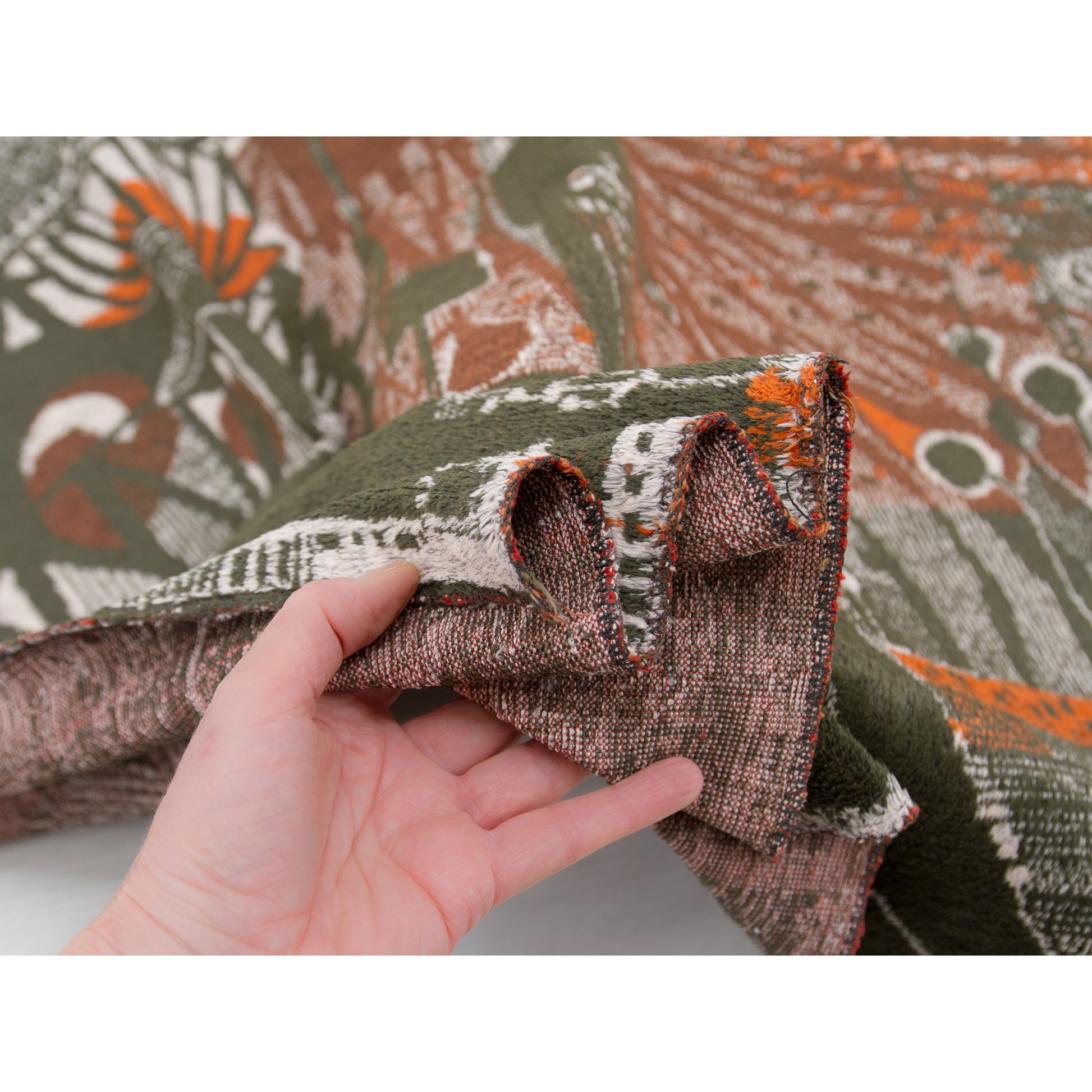 Edge of the large tapestry beautifully draped over a hand, demonstrating the perfect balance of a fabric that is delightfully soft and thin, yet undeniably sturdy and robust.