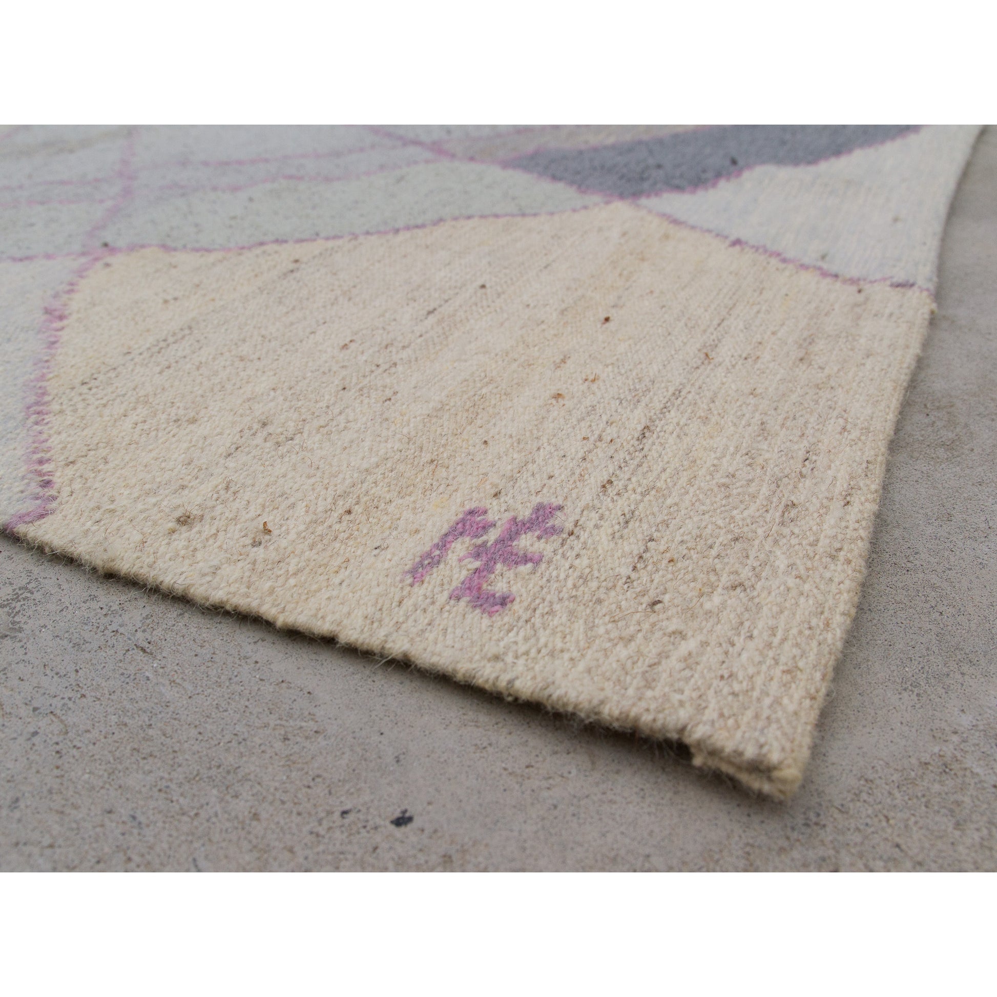 Crisp focus on the immaculate woven edge next to the artist's signature. Showing the flat, tight, flawless textile construction.