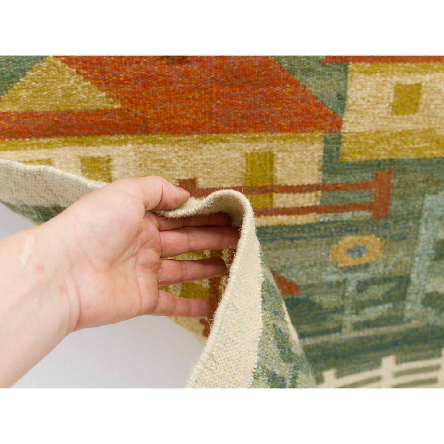 A hand lightly lifting the mid-century textile, showing the sturdy, dense flatweave construction paired with lovely woven pliability.