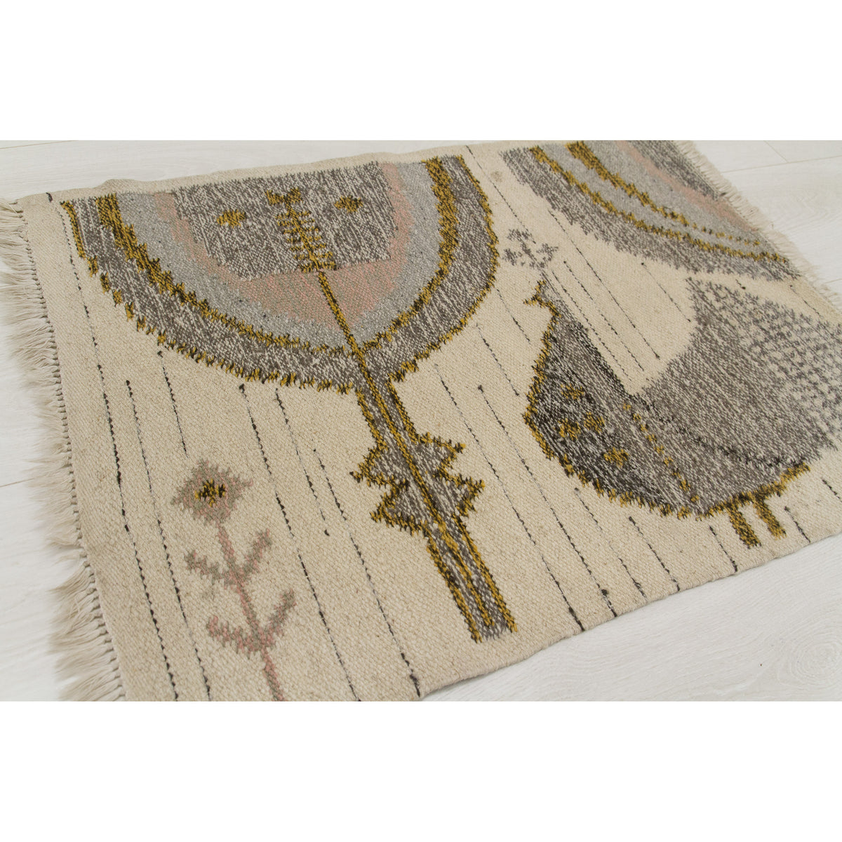 Angled flat view of the small handwoven wool rug, focusing on the abstract Tree of Life motif.
