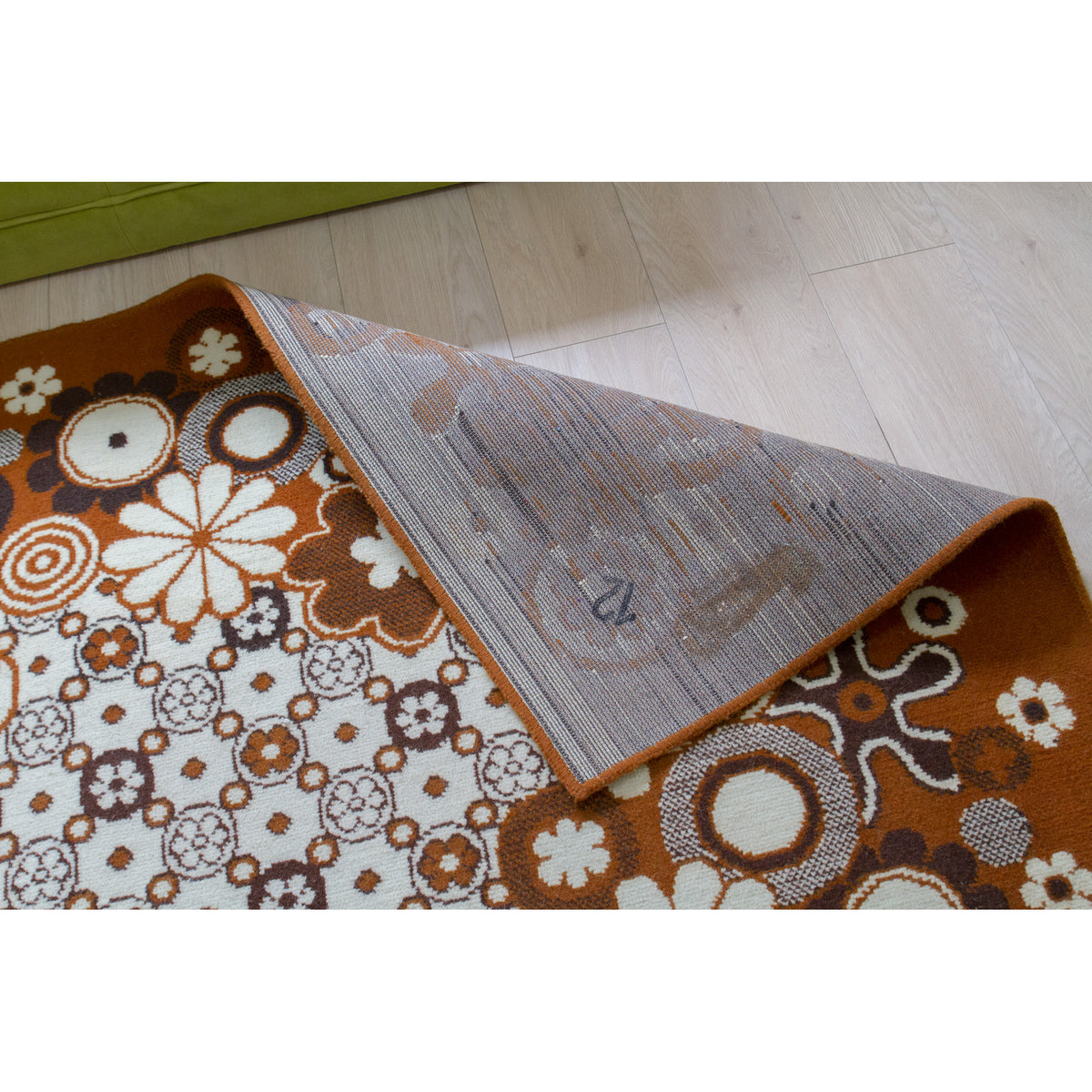 Flipped corner of flat 70s rug showing the reverse side and neat, damage-free edges