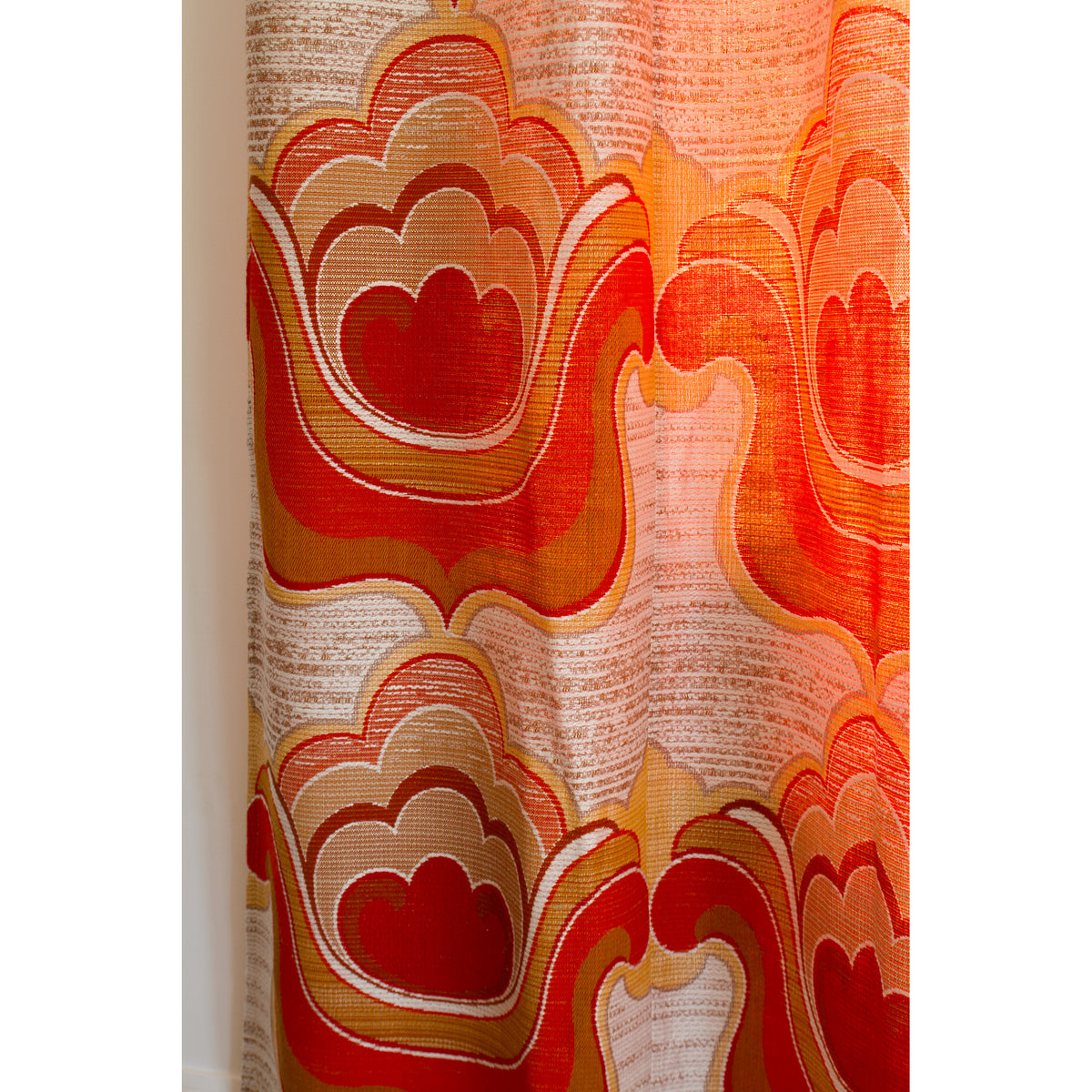 Close-up of 70s flower power curtain with big woven cloud and flower shapes in orange, red, mustard and cream