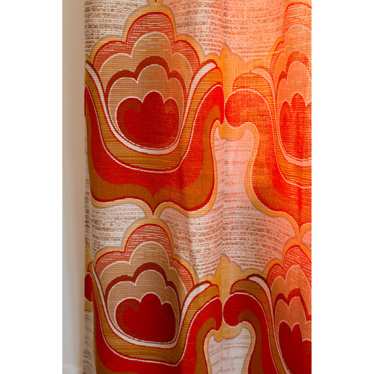 Close-up of 70s flower power curtain with big woven cloud and flower shapes in orange, red, mustard and cream