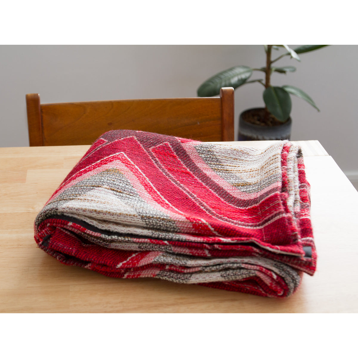 Folded vintage 70s red and grey woven fabric panel on a wooden table