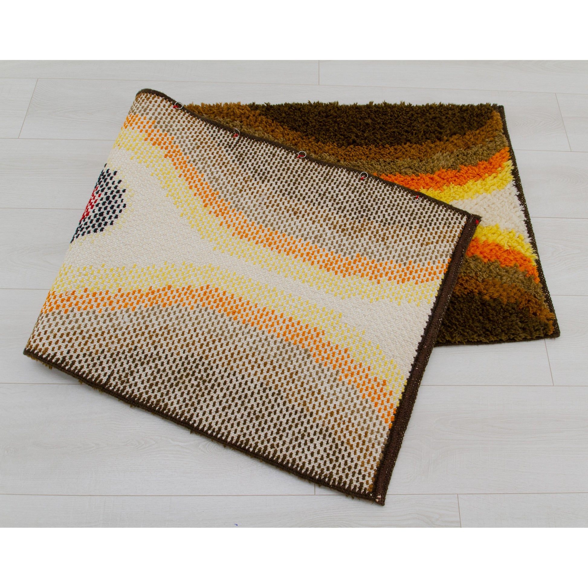 The folded retro rug highlights its flexibility and the heavy duty woven construction. Installed hardware for easy wall hanging display.