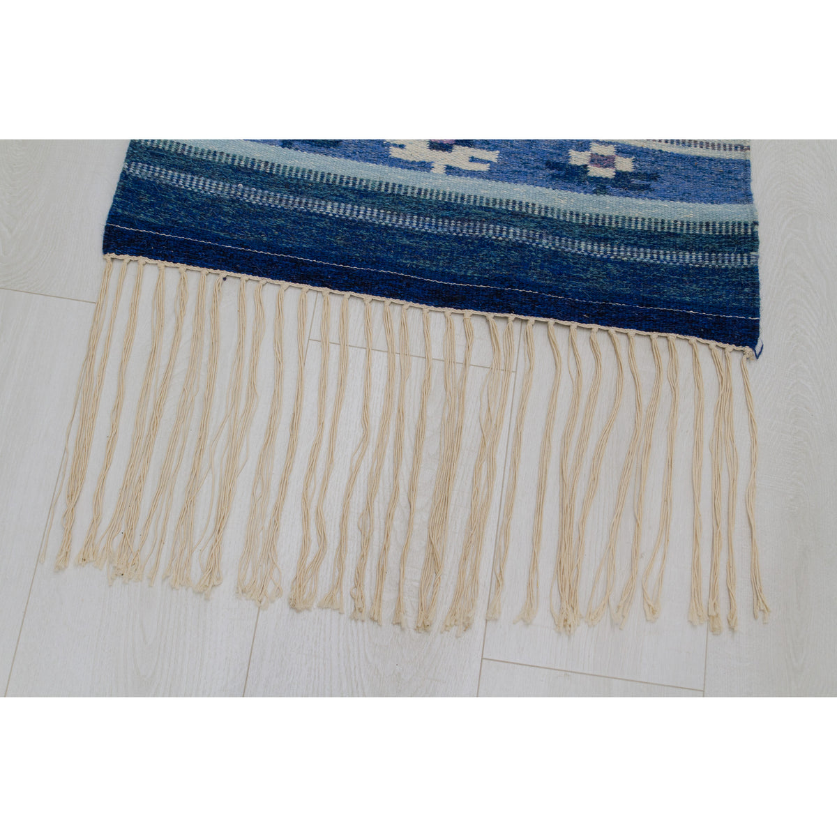 Close up of the long fringe that is approximately 6 inches long and is present on both edges of the rug.