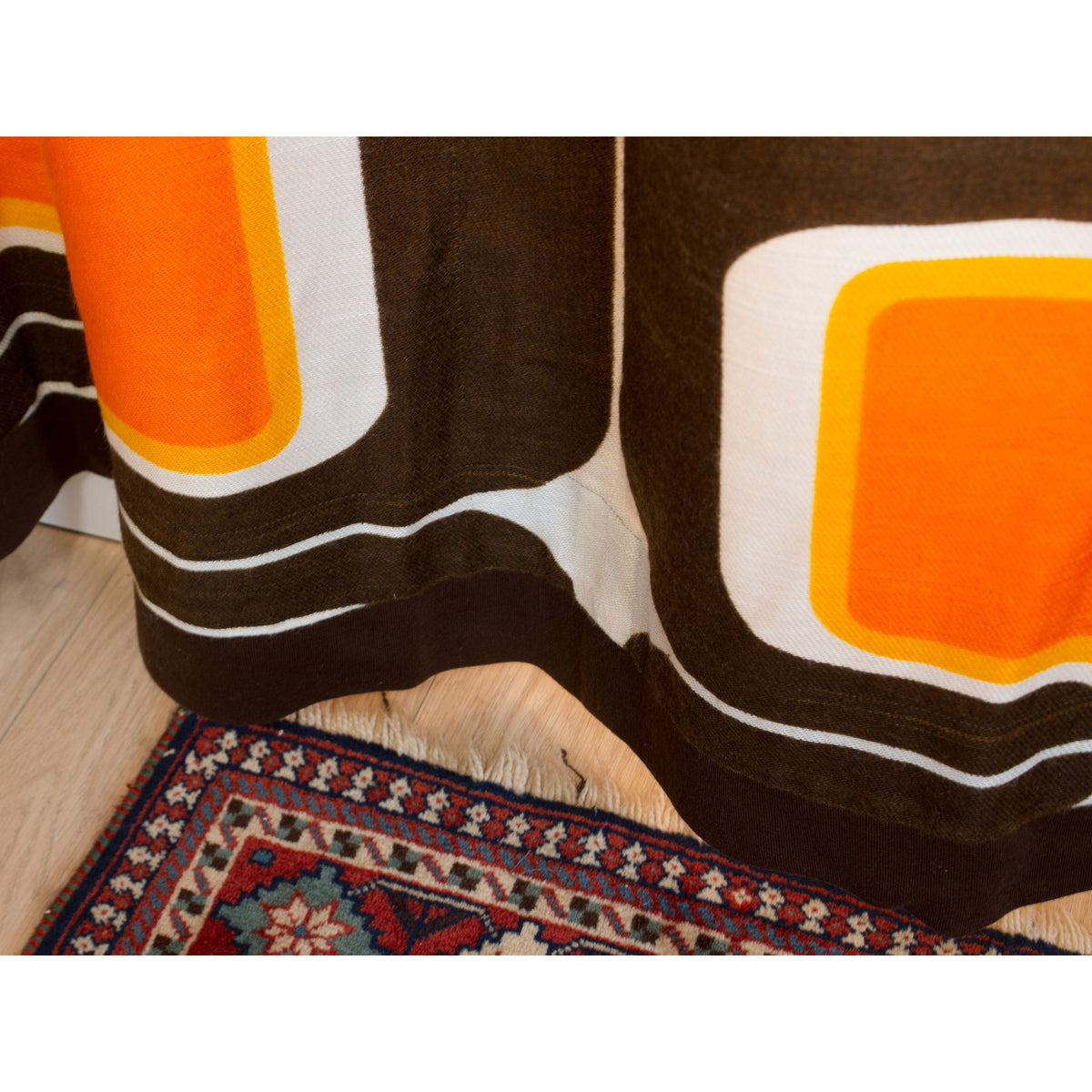 Bottom hem detail of vintage brown and orange mid century drape, neatly finished edge.