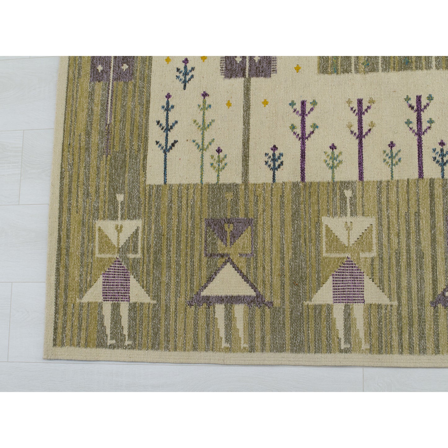 Detailed macro view of stylized female human figures woven into the wool rug using creamy beige, purple, and green yarn.