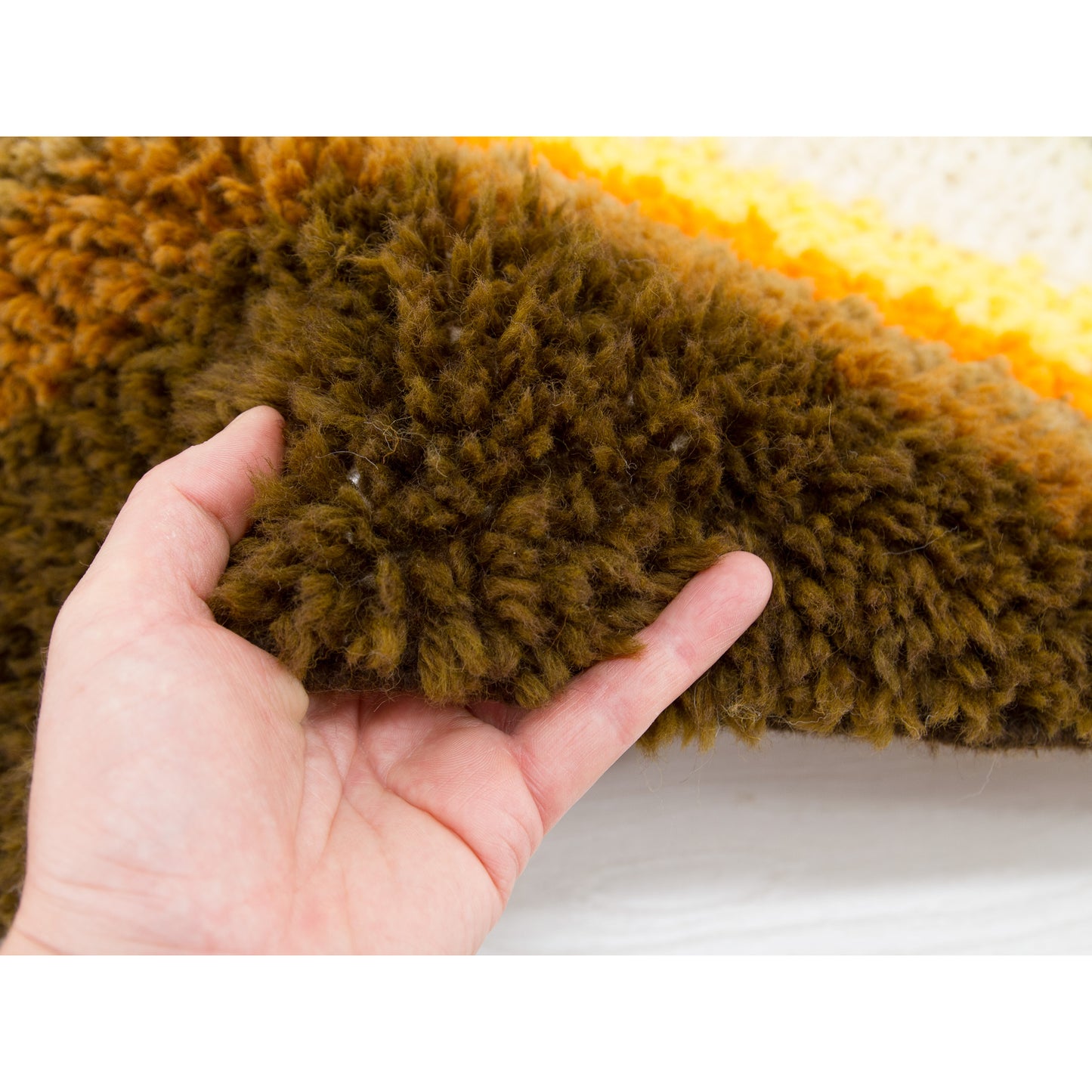 Hand softly pressing into the vintage rya rug fibers, illustrating the incredible textural warmth it brings to minimalist spaces.