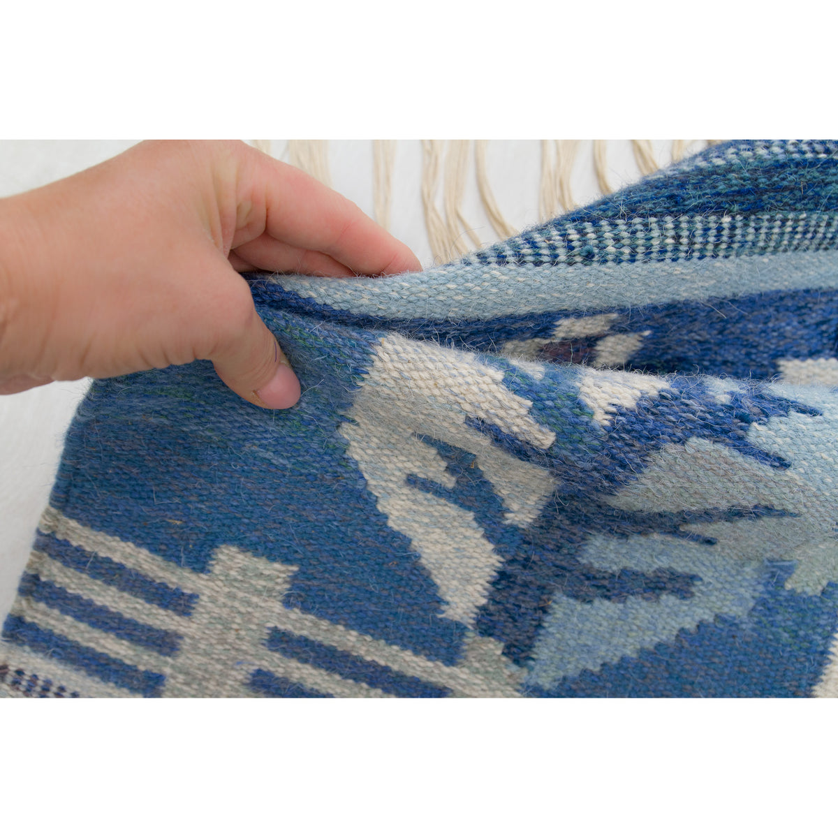 Hand scrunching the fabric to show the softness and density of the flatwoven wool rug.