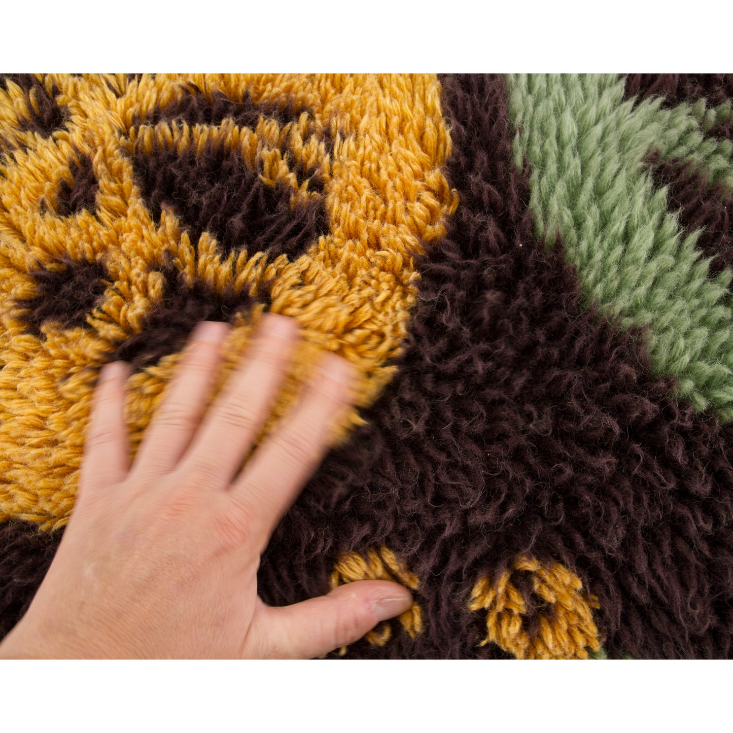 A hand hovers gently over one of the large mint green woven geometric circles, acting as an easy visual scale-reference for potential buyers comparing patterns.