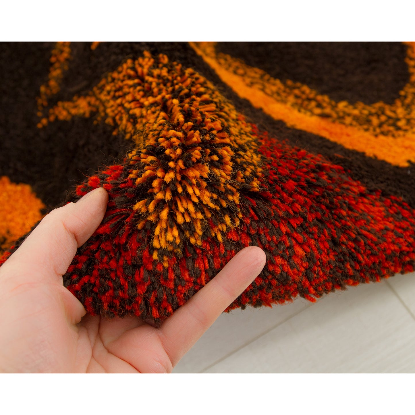 Hand gently grabbing the incredibly thick piles of the rya-style rug, proving its undeniable softness, luxurious density, and premium craftsmanship.