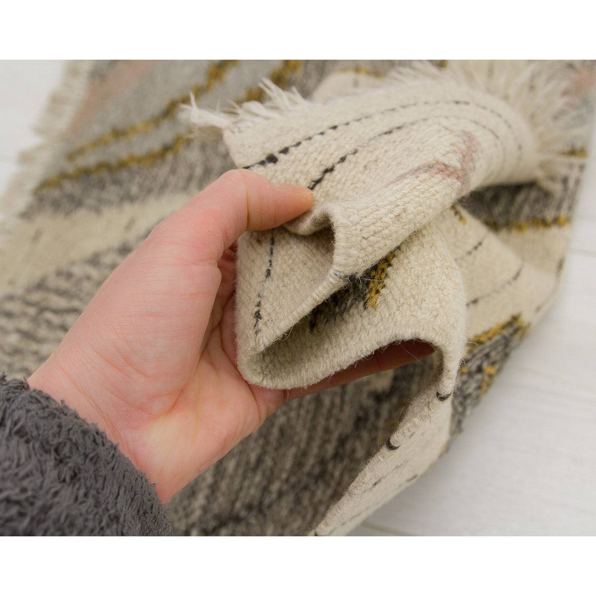 The small Eva Nemeth tapestry bunched up in a hand to demonstrate its pliability. This action shot proves the vintage wool is soft and flexible, not brittle or stiff, ensuring it will drape beautifully when hung on a wall.