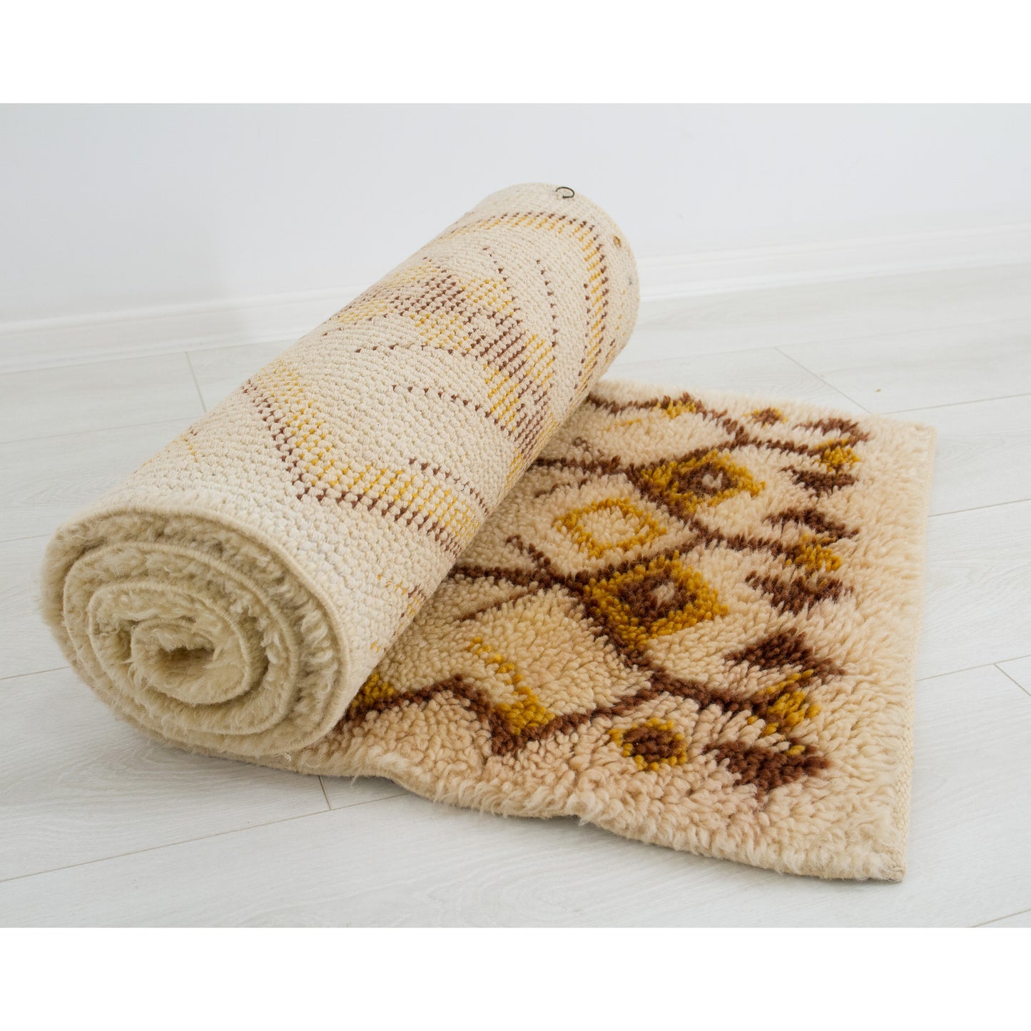 The 180-centimeter tapestry rolled up effortlessly onto itself across a bright floor, visualizing the luxurious thickness, strong foundation, and pliable texture of the vintage wool rug.