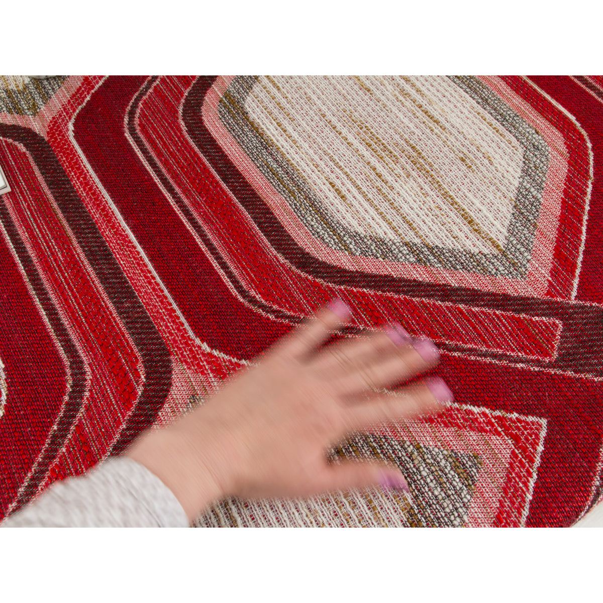 Close-up of hand on heavy retro woven fabric with red hexagon pattern and slub texture