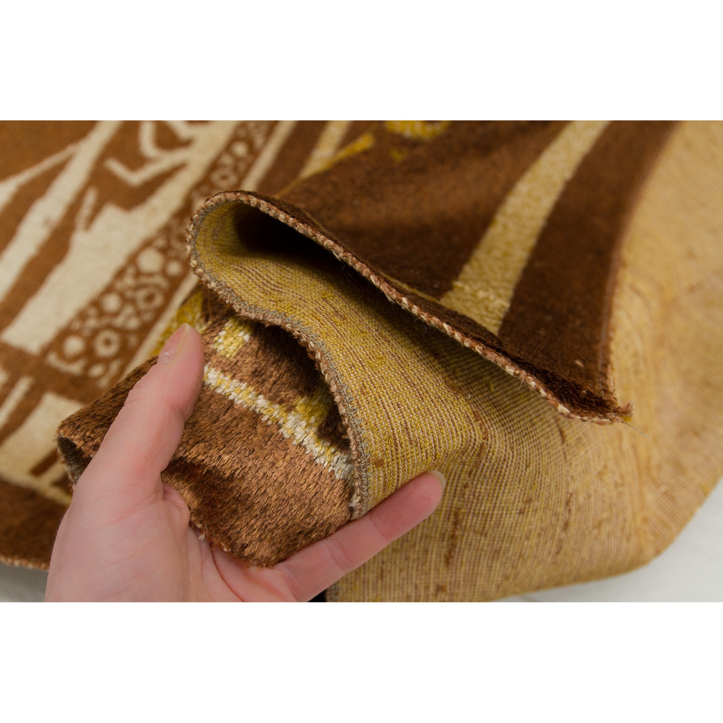 Hand holding the folded edge of the tapestry, highlighting the substantial thickness of the double-layer woven moquette. Durable and heavy textile suitable for wall hanging or rug use.