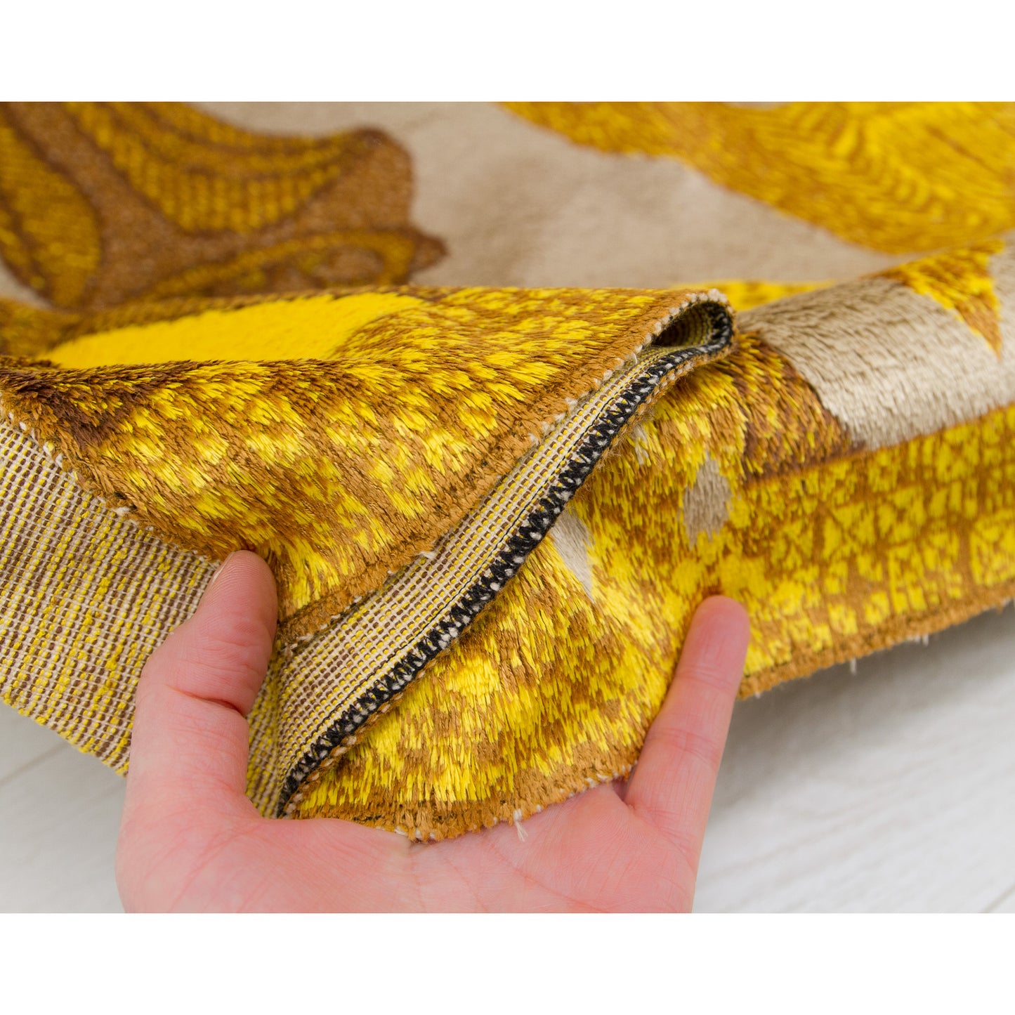 Close up on the fabric draped effortlessly in hand, displaying the incredibly fine piles alongside a completely secure, damage-free woven border.