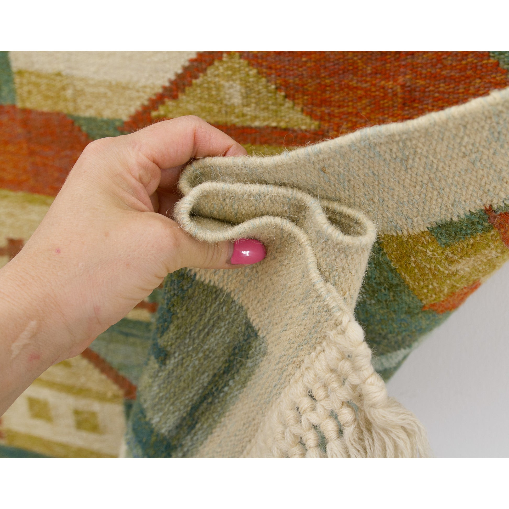 Hand draping the edge of the vintage tapestry, emphasizing the thick wool weft over cotton warp and wonderfully neat, unblemished side borders.