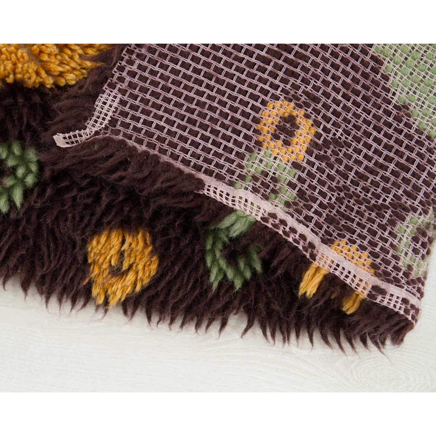 Detailed extreme close-up showing absolute seller honesty: revealing the canvas backing edge where a few tiny yarn loops have worn away over the decades, completely invisible from the front due to long pile overlay.