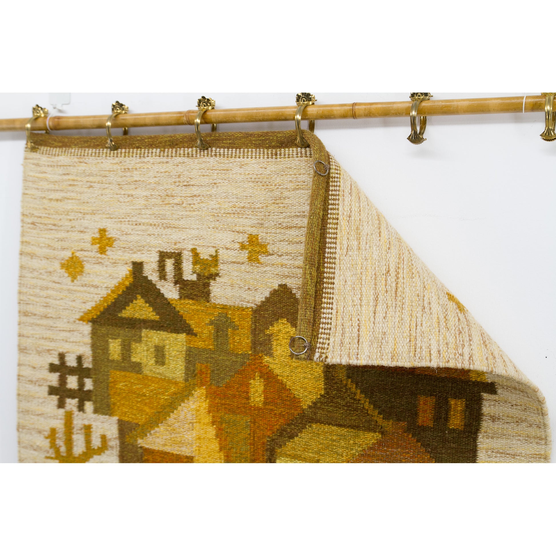 Looking under the top hem folded down on the wall, visualizing exactly how the warm-toned artwork can be quickly mounted with regular decorative metal clips.