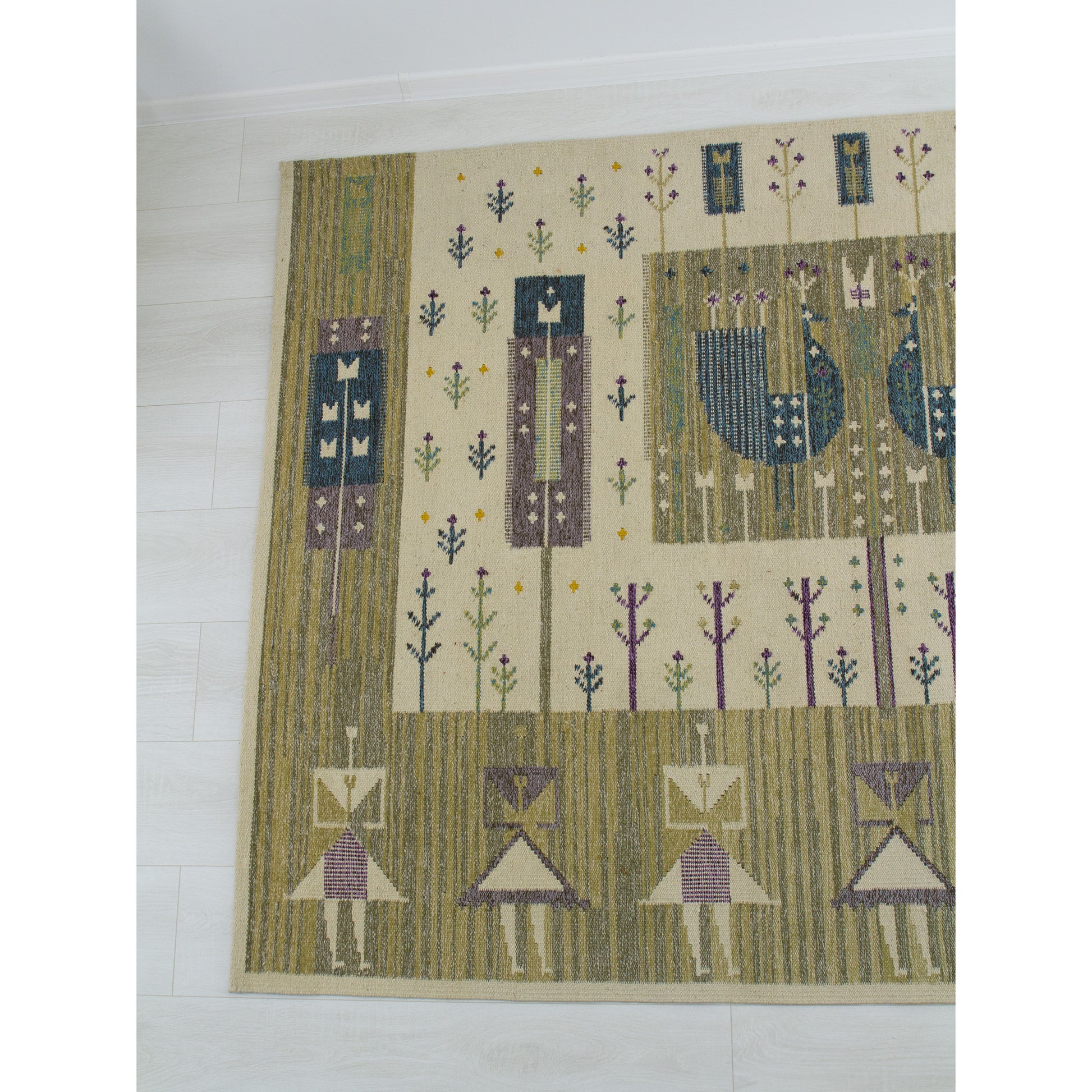 Left half detail of 1970s flatwoven tapestry showing olive green and slate blue geometric flowers and stylized human figures.