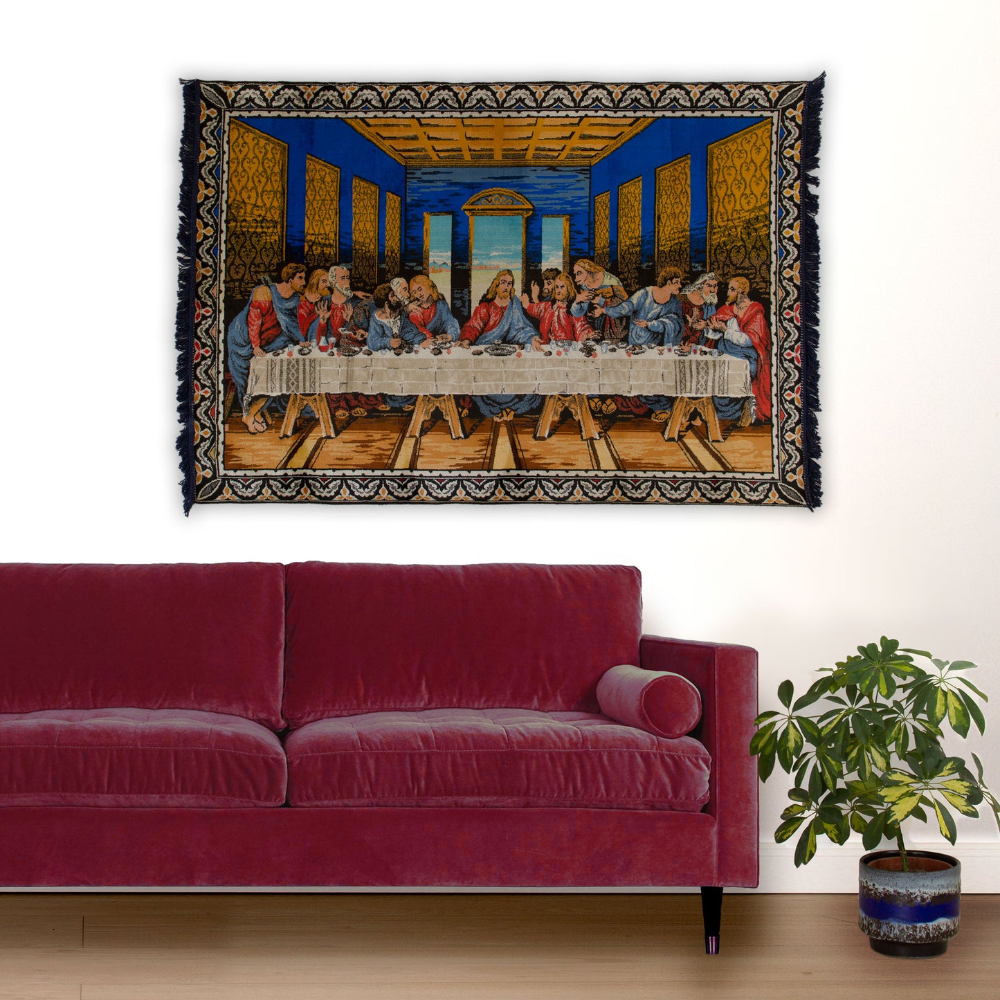 A large 1960s vintage Last Supper tapestry featuring brilliant cobalt blue and warm brown hanging majestically on a white wall behind a rich cherry red modern sofa.