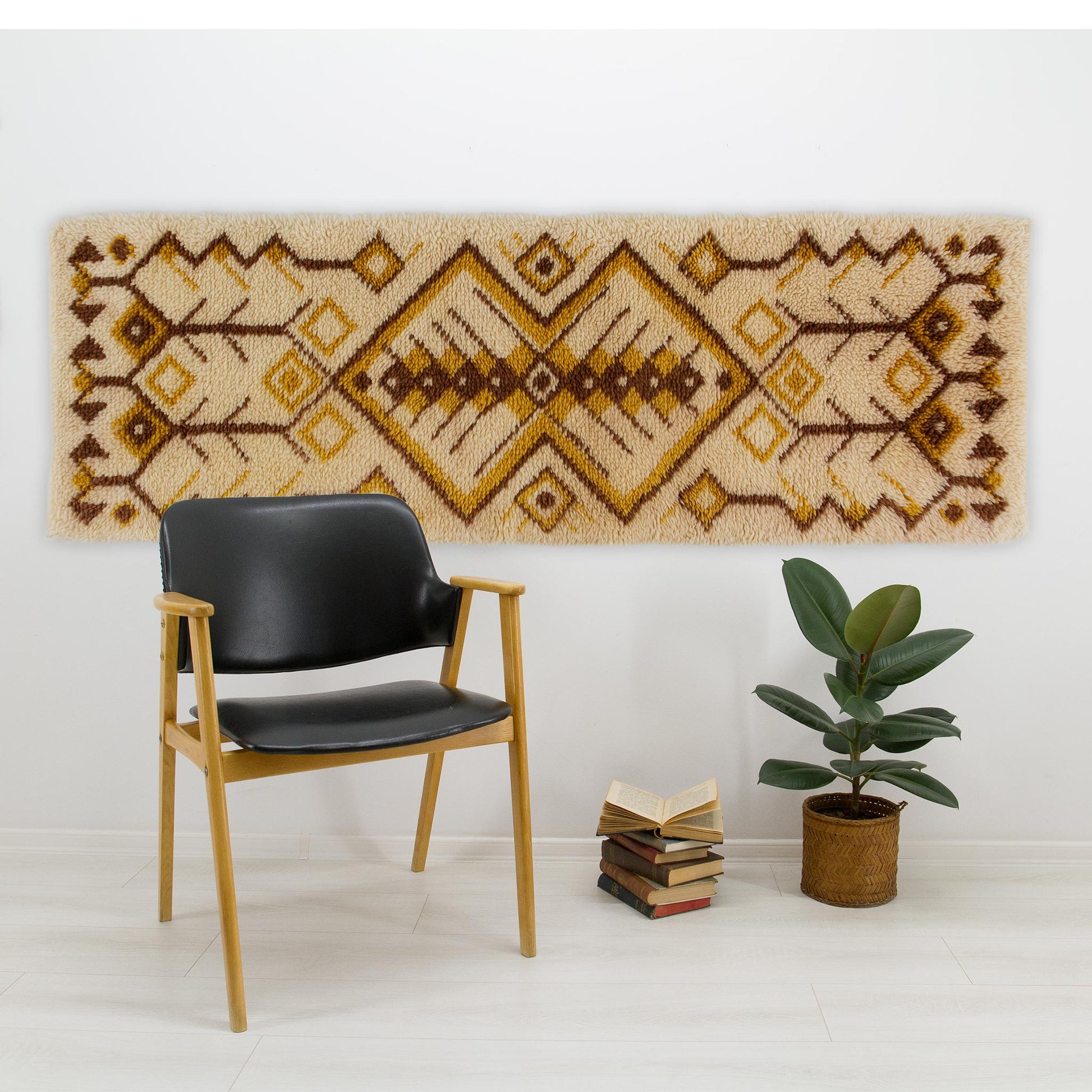 The heavy Hungarian wool wall hanging displayed horizontally as grand textured art behind a sleek black leather chair and a potted green plant.