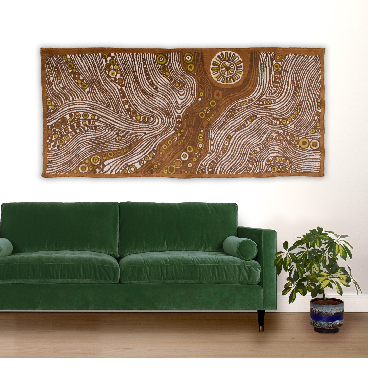 Living room styling featuring a lush green velvet sofa placed under an epic 67-inch mid century modern wall hanging. The velvet-like tapestry adds rich texture and hypnotic retro patterning to the room.