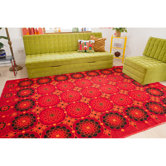 Full view of a retro 1970s themed living room, showcasing a vintage space age style area rug and lime green modular sofa set. The red Flower Power rug anchors the room and defines a strong 1970s space age design.