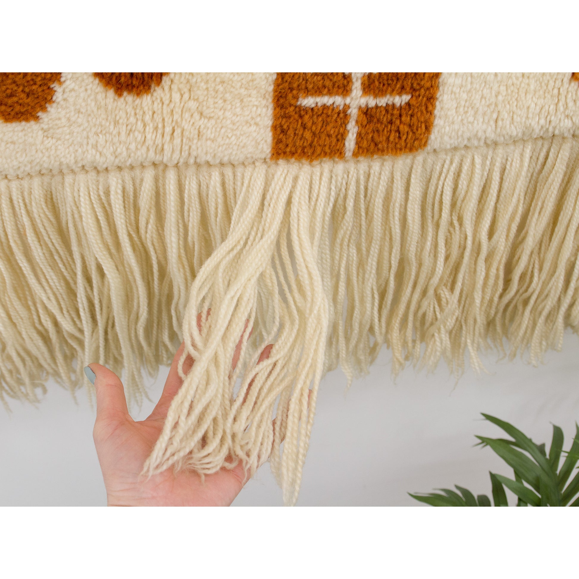 Detail of the extra-long wool fringe at the bottom edge, adding vertical movement and softness to the horizontal art piece.