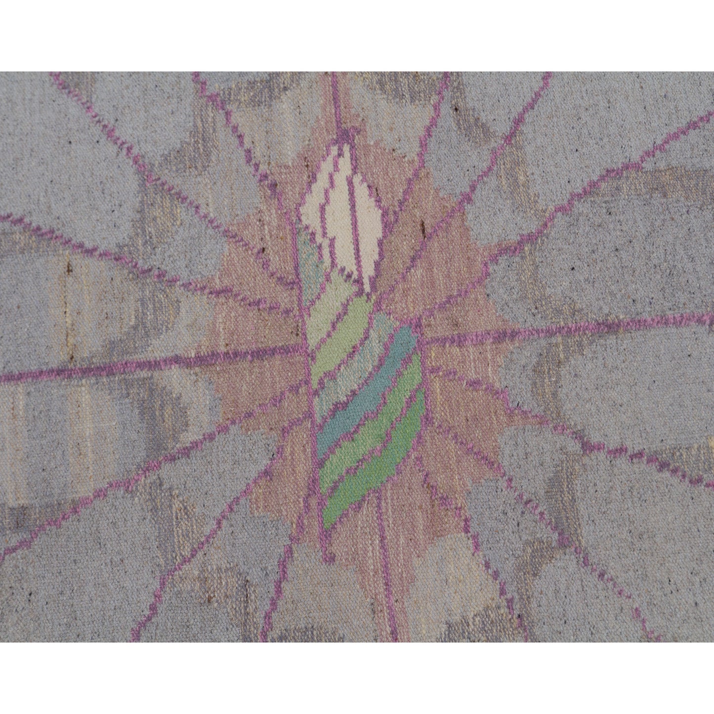 Close up on the center motif. A beautifully stylized organic flower shape framed by spiderweb-like intersecting pink woven lines on a soft dove-grey background.