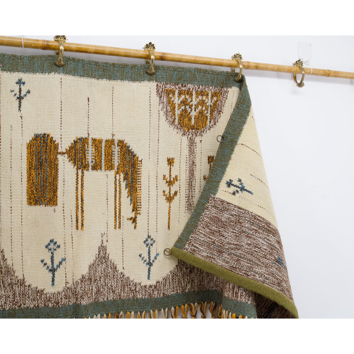 The top edge of the textile is folded downwards, clearly showing the buyer the convenient small metal hanging rings that have been securely hand-sewn to the hem.